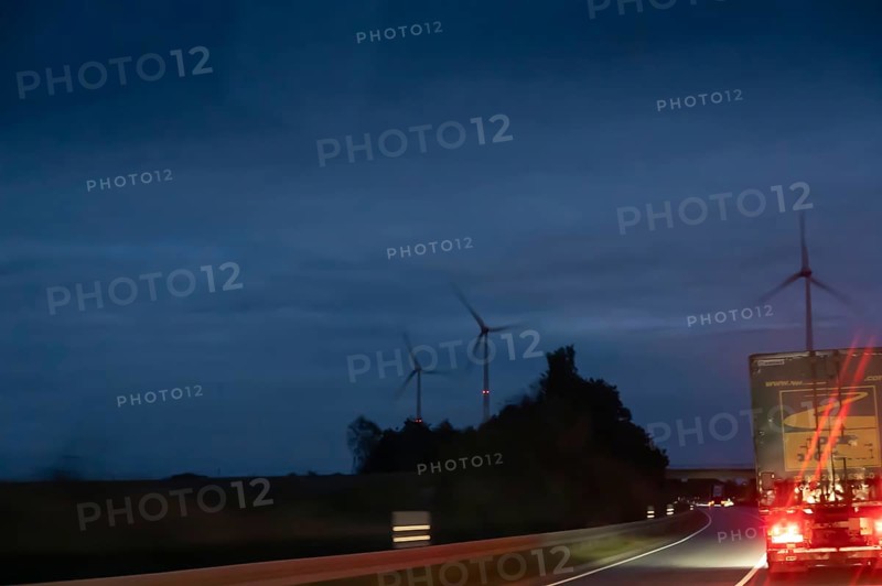 Truck on federal highway at night, wind turbine lights on the left, Schleswig-Holstein, Germany