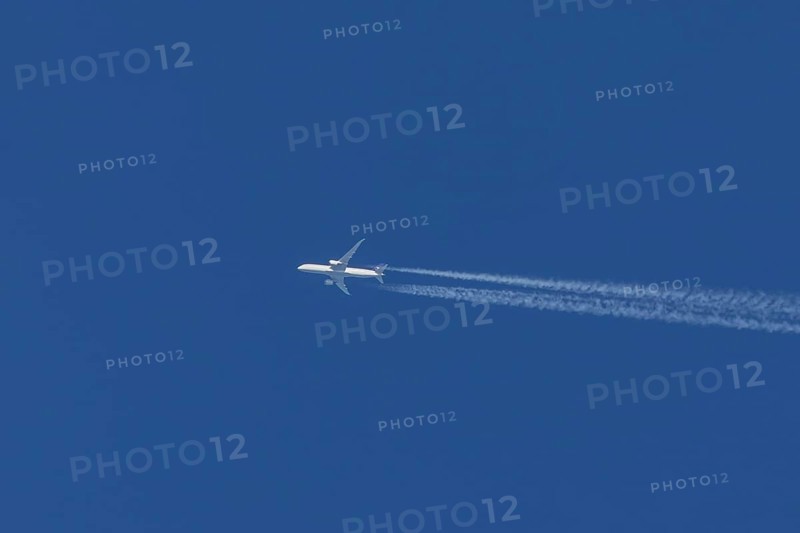 Jet passenger aircraft flying in a blue sky with contrails or vapour trails behind, England, United Kingdom