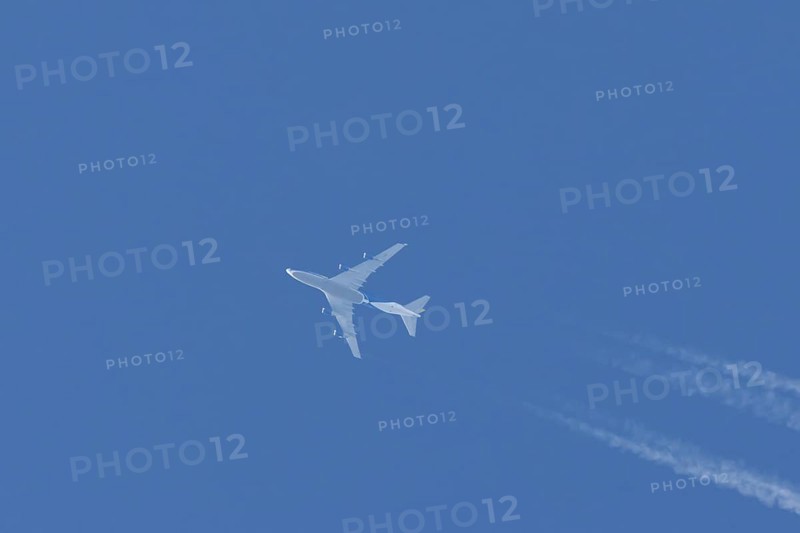 Boeing 747 jumbo jet cargo aircraft flying in a blue sky with contrails or vapour trails behind, England, United Kingdom