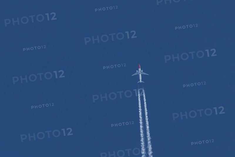 Boeing 737 jet passenger aircraft of Norwegian Air airlines flying in a blue sky with contrails or vapour trails behind, England, United Kingdom