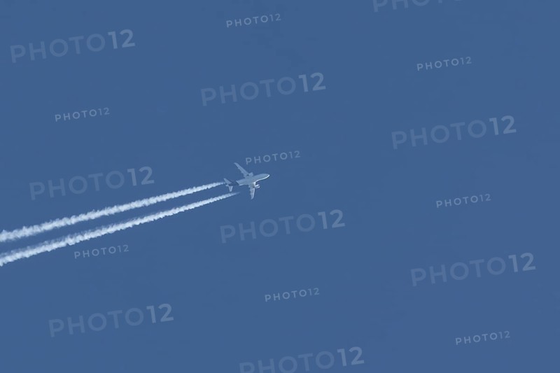 Airbus jet passenger aircraft flying in a blue sky with contrails or vapour trails behind, England, United Kingdom