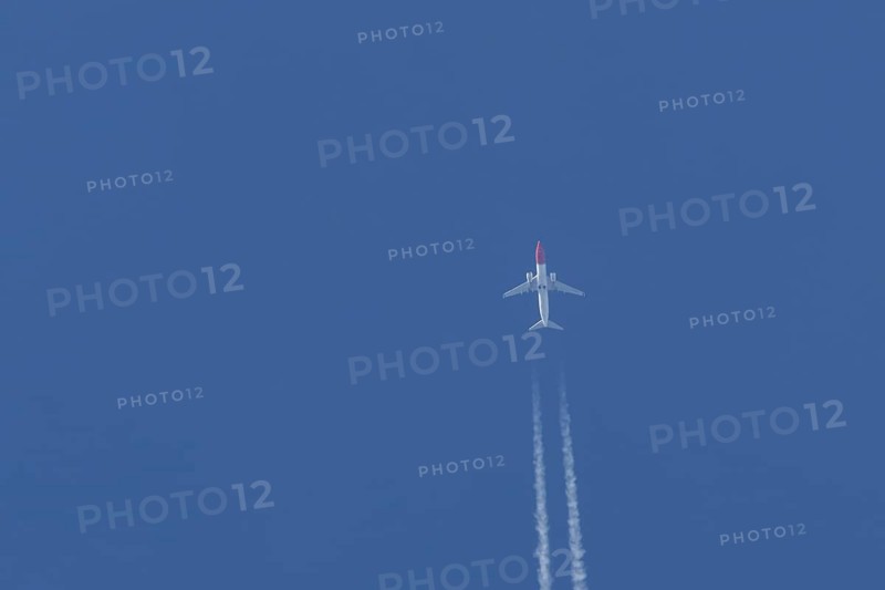 Boeing 737 jet passenger aircraft of Norwegian Air airlines flying in a blue sky with contrails or vapour trails behind, England, United Kingdom