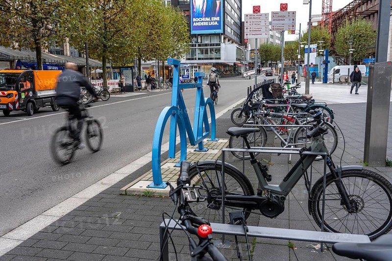Bicycle parking spaces, with so-called leaning bars and a large blue bicycle silhouette, to make parking spaces visible at Bochum City Hall, North Rhine-Westphalia, Germany