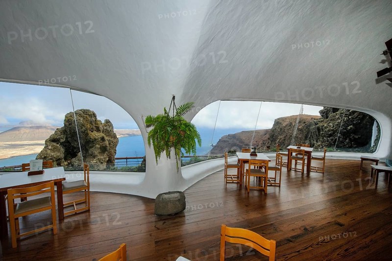 Interior of café with panoramic window in building designed by Cesar Manrique with the collaboration of Jesús Soto and architect Eduardo Caceres without right angles corners on viewpoint tourist attraction El Mirador del Río on the summit of the 474 meter high Risco de Famara in Famaramassiv with panoramic view of the Chinijo Archipelago, La Graciosa island, Lanzarote, Canary Islands, Canary Islands, Spain