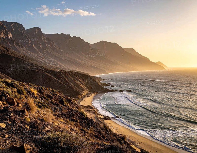 Desert landscape converges with ocean along a rugged coastal area, shore break at cliffs, blue cloudy sky at sunset, dry landscape in an aerial drone view, AI generated