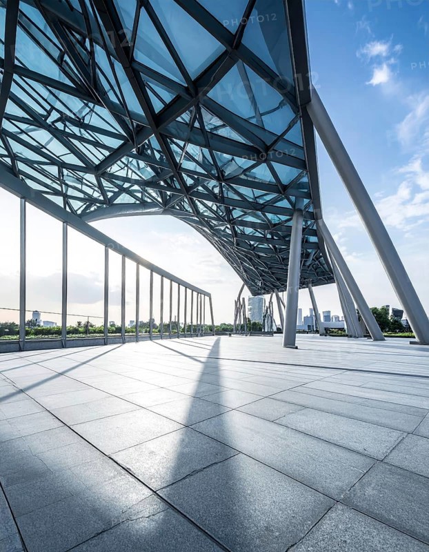 Modern architectural framework with glass and steel structure, glass facade with a greed of steel arrows, blue sky with a soft golden light of a sunrise, AI generated