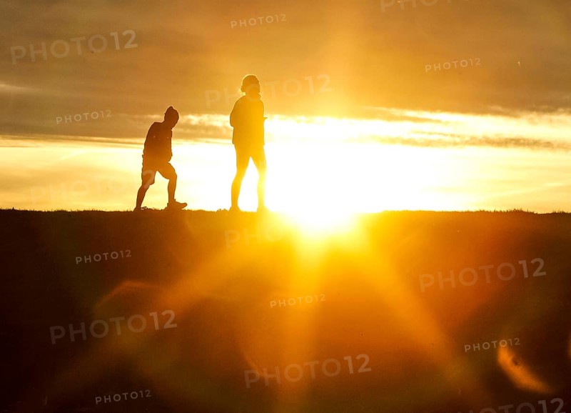 Woman and child walk across a dike on the island of Fehmarn at sunset, 13.10.2025, Fehmarn, Schleswig-Holstein, Germany