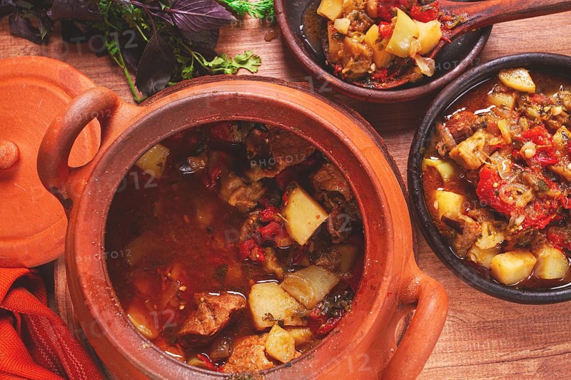 Chanakhi, a Georgian dish. in a clay pot, on a wooden table, stewed meat with vegetables, homemade, no people
