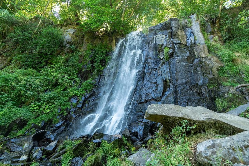 Vaucoux waterfall cascades gracefully over dark rocks, surrounded by lush greenery, Auvergne Volcanoes Regional Park, Puy de Dome., Auvergne-Rhone-Alpes, France