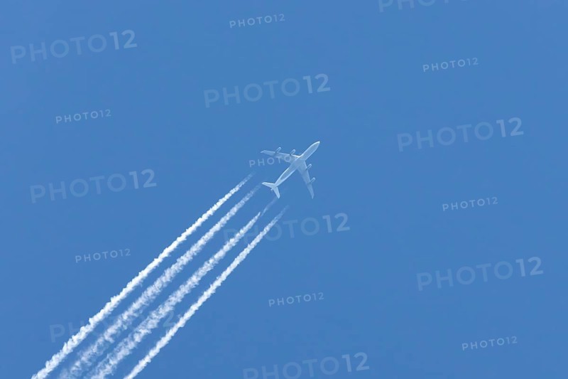 Airbus A340-300 jet aircraft of Lufthansa airlines in flight in a blue sky with vapour trails or contrails behind, England, United Kingdom