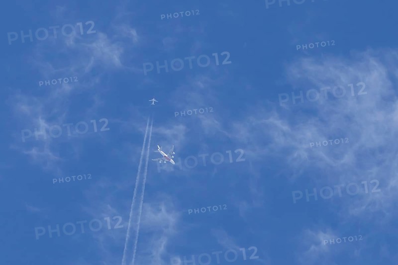 Two airliners Airbus A380 jet passenger aircraft of Emirates airlines and a Boeing 737 of Norweign Air flying in a blue sky, England, United Kingdom