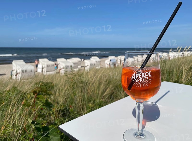 Glass of Aperol Spritz on a table overlooking the beach, Baltic resort Kühlungsborn, Mecklenburg-Vorpommern, Germany