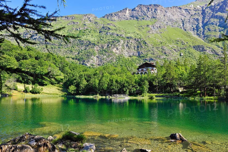 View of mountain lake Lago Grande near Moncenisio in Val Cenischia in the Graian Alps, behind it chalet on the lake, Moncenisio, Piedmont, Italy