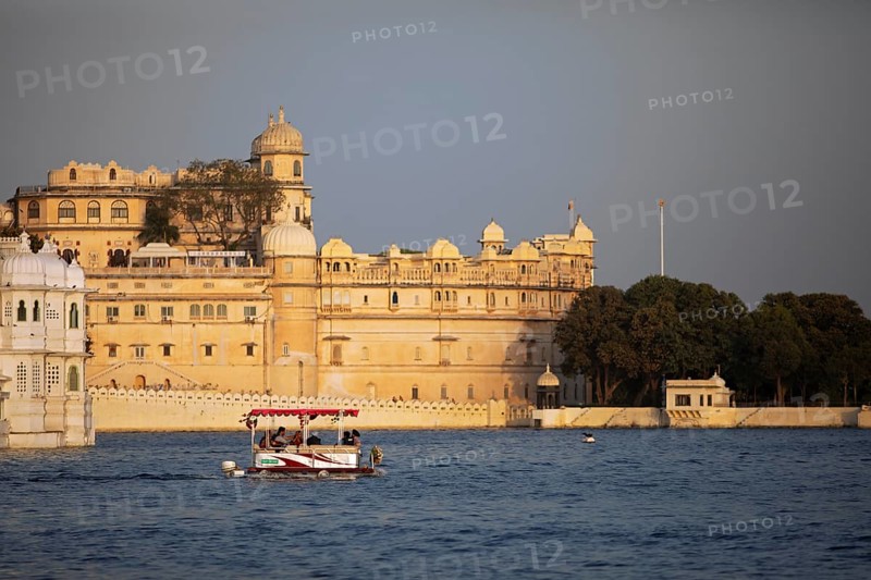Excursion boat on Lake Pichola, behind the City Palace in the evening light, Udaipur, Rajasthan, India
