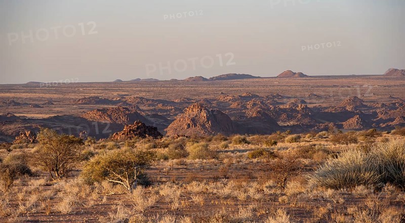 Desert landscape in the evening light at sunset, barren landscape with hills of stacked rocks, Erongo, Damaraland, Namibia