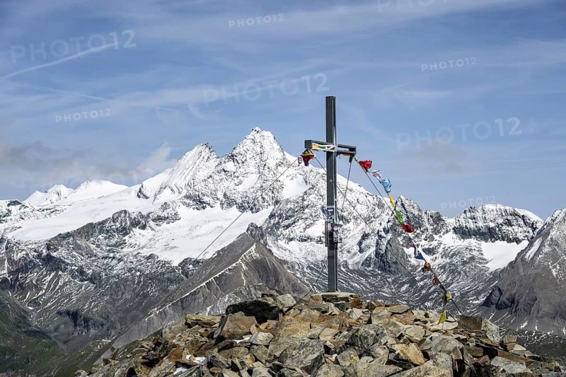 Summit cross of the summit Böses Weibl, behind summit of the Großglockner with snow, Schober group, Hohe Tauern National Park, Carinthia, Austria