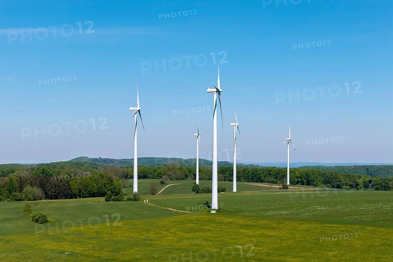 Wind turbines on a green field surrounded by forest under a blue sky, Swabian Alb, Baden-Württemberg, Germany