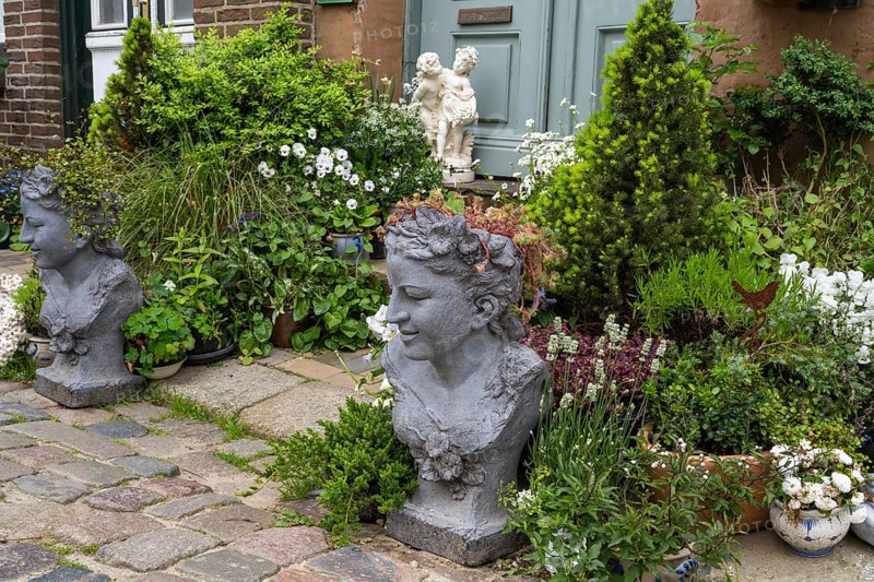 House entrance with blooming flowers, conifers and stone busts, Old Town, Husum, North Frisia, Schleswig-Holstein, Germany