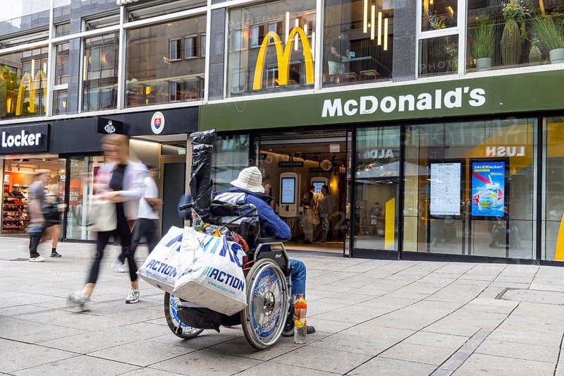 A man in a wheelchair in the Königstraße pedestrian zone in front of a branch of the McDonald's fast food chain. Stuttgart, Baden-Württemberg, Germany