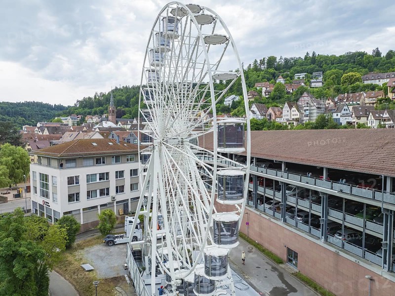 A large Ferris wheel in the middle of an urban environment with a cloudy sky, Ferris wheel construction for the 950th anniversary of the city of Calw, Black Forest, Germany