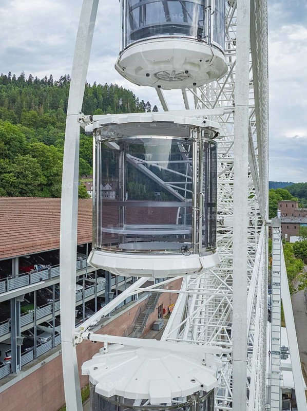 Three gondolas of a Ferris wheel, surrounded by green landscape and sky, Ferris wheel construction for the 950th anniversary of the town of Calw, Black Forest, Germany