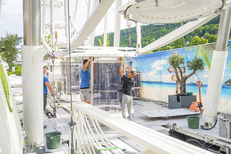 People aligning a cabin in a Ferris wheel in front of a landscape scenery, Ferris wheel construction for the 950th anniversary of the town of Calw, Black Forest, Germany