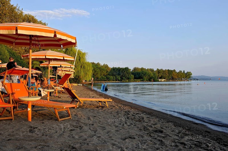Beach, deckchairs, sunshades at the lido, Lake Bolsena, Lago di Bolsena, volcanic crater lake, calm smooth water surface, warm evening light, Bolsena, Province of Viterbo, Lazio, Italy