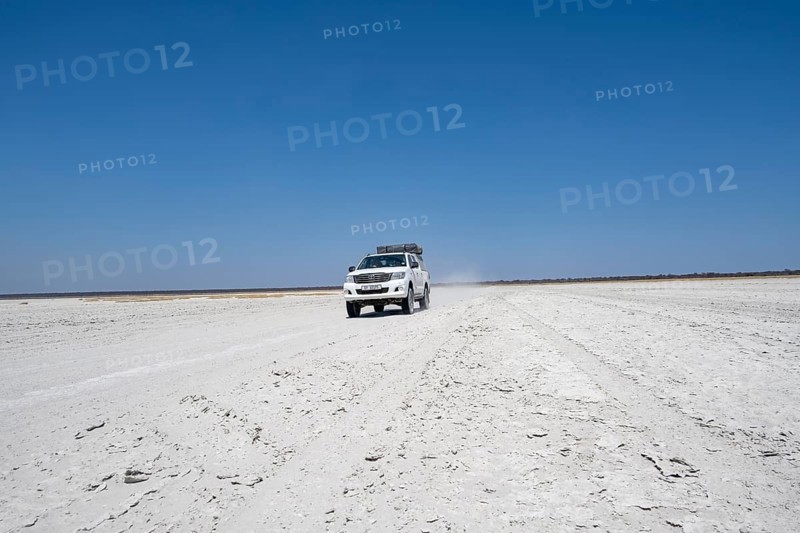 Off-road vehicle driving on a wide empty salt pan, Makgadikgadi Salt Pans, Botswana