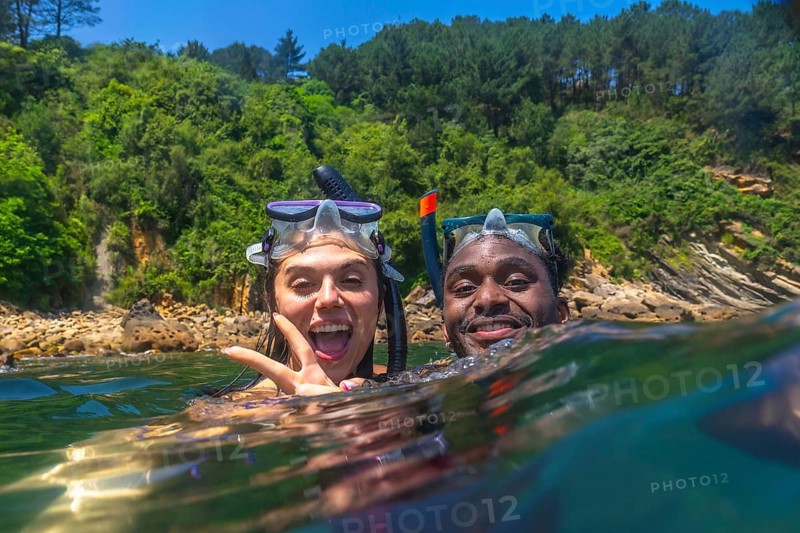 Interracial couple snorkeling together in the vibrant ocean, enjoying a fun filled summer vacation and creating joyful memories