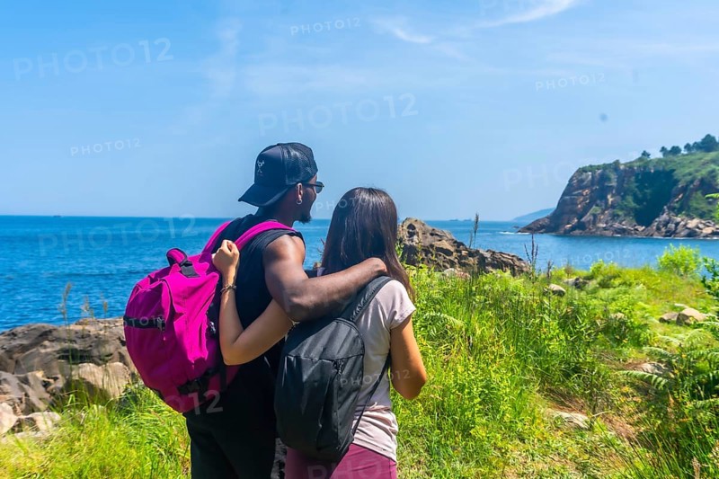 Couple savoring a stunning ocean view during a summer hike, celebrating the beauty of nature and their shared adventure together