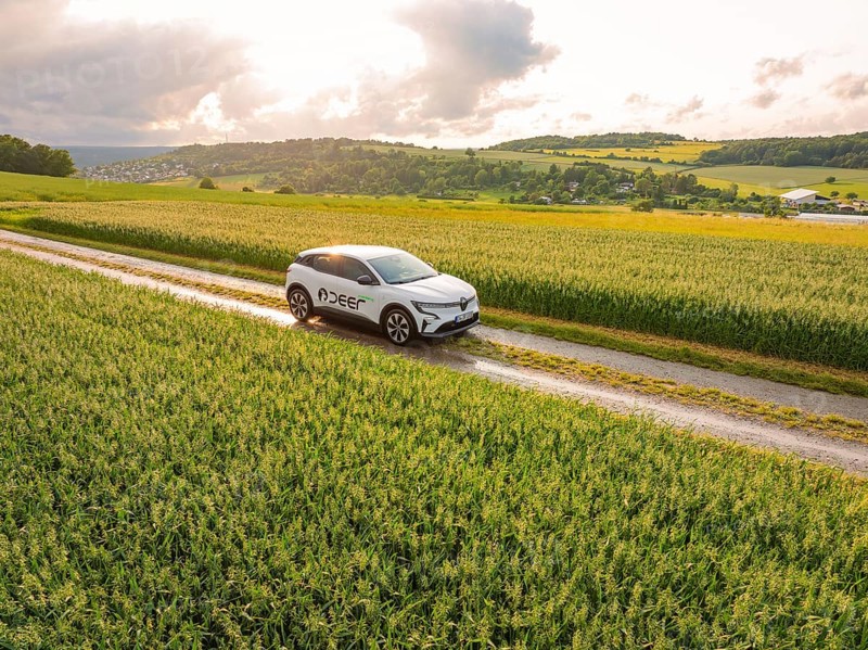 A car moves along a path through green fields with a wide view of the landscape, Deer E- CarSharing, Renault Megane electric car, Calw, Black Forest, Germany