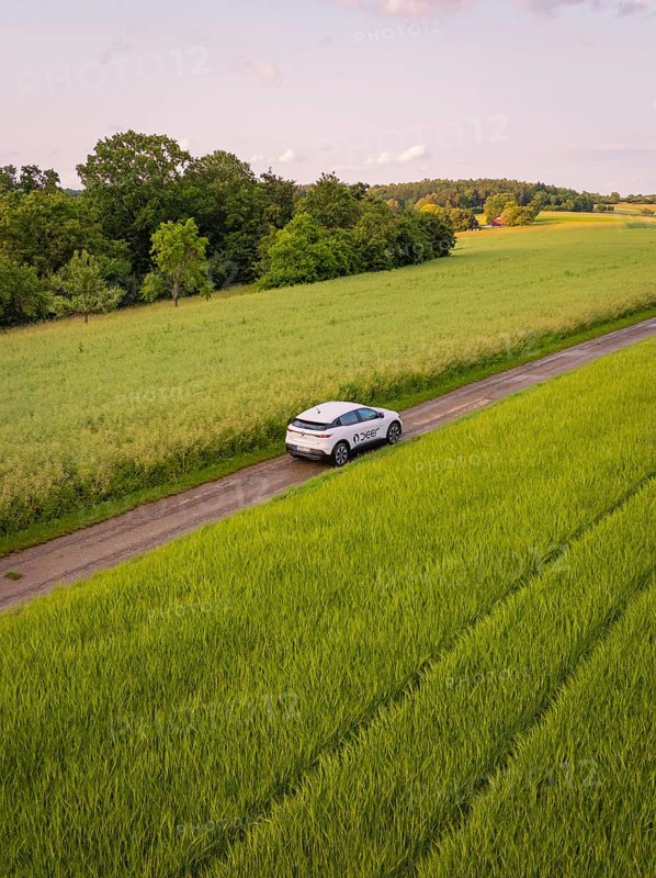 Car drives through rural route surrounded by green fields and summer landscape, Deer E- CarSharing, Renault Megane electric car, Calw, Black Forest, Germany
