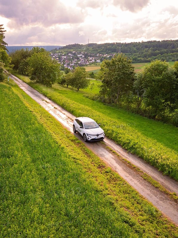 Car drives on narrow road through green landscape with village on the horizon, Deer E- CarSharing, Renault Megane electric car, Calw, Black Forest, Germany