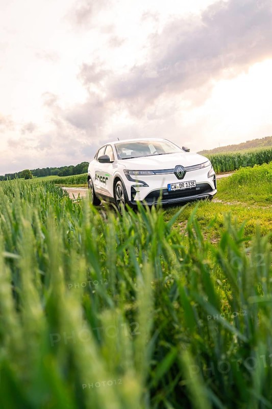White car surrounded by vegetation and fields under a partly cloudy sky, Deer E- CarSharing, Renault Megane electric car, Calw, Black Forest, Germany