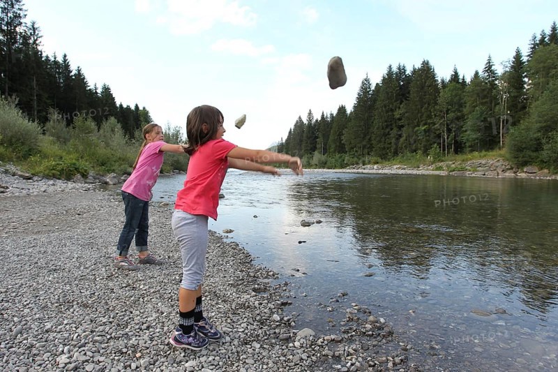Girls, children throwing stones into a river, activity with children in nature, Allgäu, Bavaria, Germany, Allgäu, Bavaria, Germany