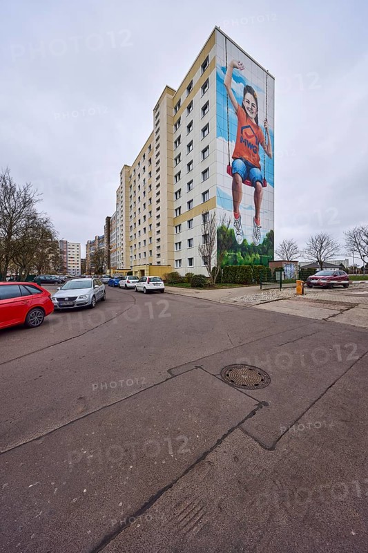 High-rise buildings, residential building, facade, window, advertising painting, MWG-Wohnungsgenossenschaft eG Magdeburg, car park with vehicles, bare wintry trees, diffuse light, cloudy, Lumumbastraße, Magdeburg, state capital, independent city, Saxony-Anhalt, Germany