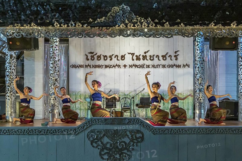 Traditional Thai dancers perform on a lighted stage at the night market in downtown Chiang Rai, Thailand