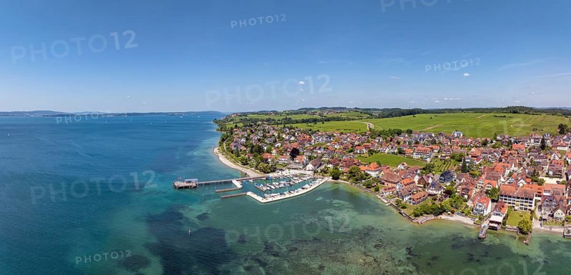 Luftbild, Panorama von der Bodenseegemeinde Hagnau, Winzerdorf und beliebter Ferienort am Bodensee, dahinter Rebhänge, auf denen hauptsächlich die Weinsorten Müller Thurgau und Blauer Burgunder angebaut werden. Am Seeufer der am 23.Mai 2025 eingeweihte, neue Westhafen, Yachthafen mit der Schiffanlegestelle, Bodenseekreis, Baden-Württemberg, Deutschland