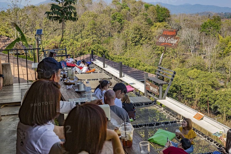 Customers eat, drink and relax on a net suspended over the hillside at the Akha Cottage restaurant and coffee shop in Chiang Rai, Thailand