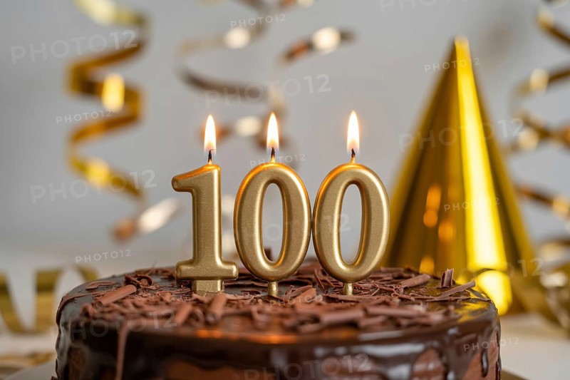 Chocolate cake with golden candles spelling 100. Celebration of longevity and reaching 100 years with festive gold decorations. Generative ai, AI generated