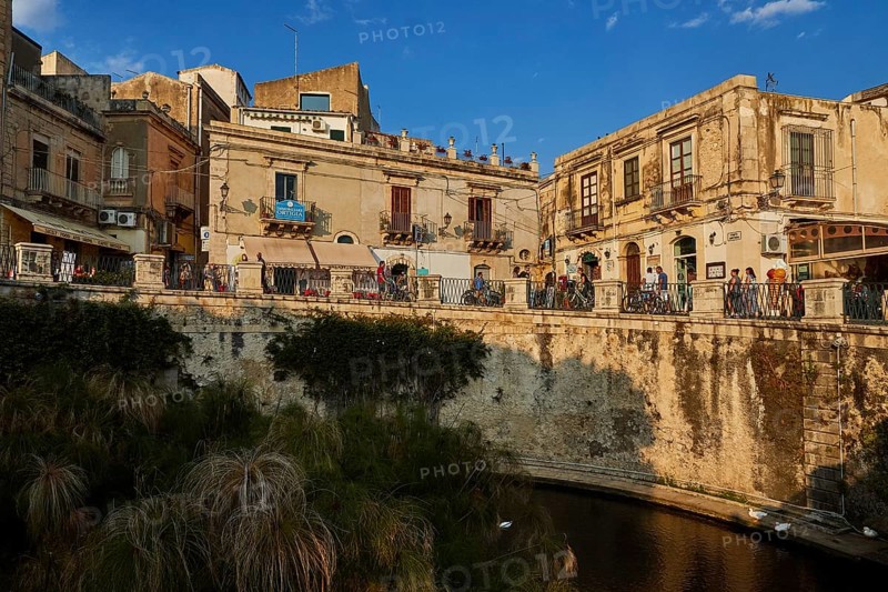 Largo Aretusa, Fonte Aretusa, View of a busy bridge and old buildings under a blue sky, Ortigia Island, Isola di Ortigia, Historic old town, Syracuse, Sicily, Italy
