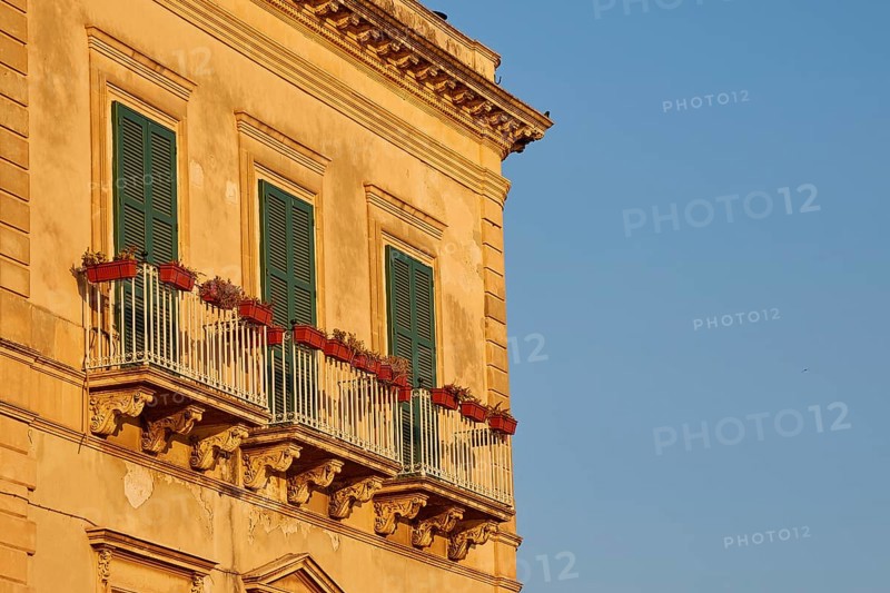 Facade of a building with balconies and green shutters in the sunlight, Ortigia Island, Isola di Ortigia, Historic Centre, Syracuse, Sicily, Italy