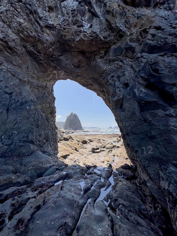 Large rock with a hole and people in the foreground, Hole in The Wall, Rialto Beach, Olympic National Park, Washington, USA, North America