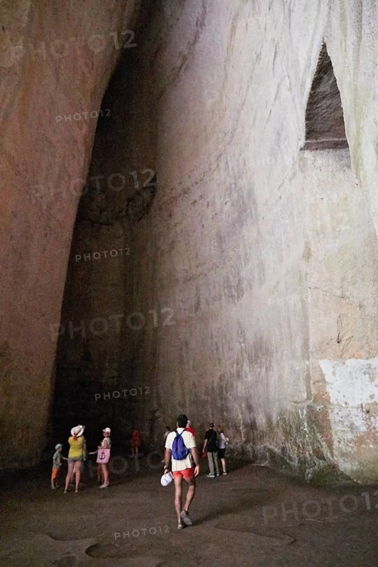 Cave Ear of Dionysus, group of people in a high rock cave, exploring the natural structure, Neapolis Archaeological Park, Syracuse, Sicily, Italy