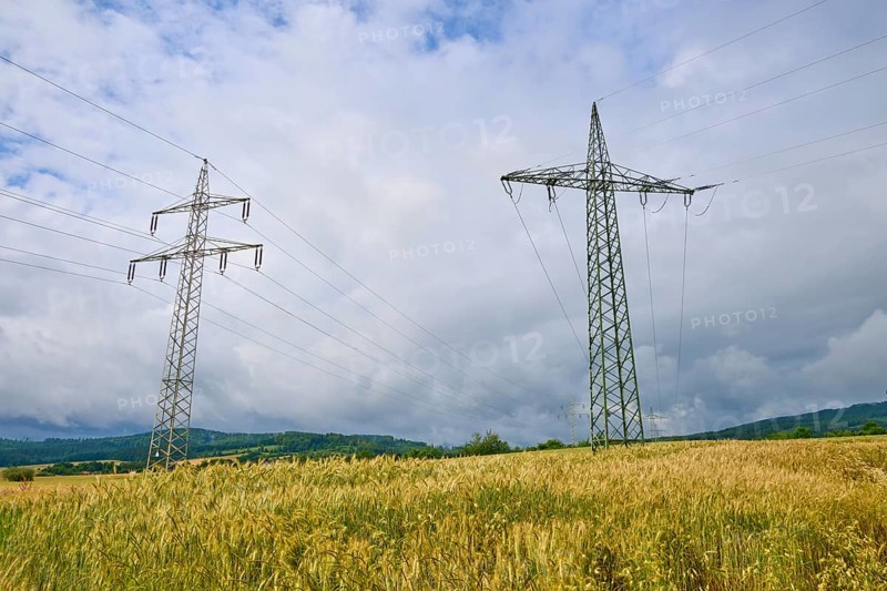 Crop field with electricity pylons, under a cloudy sky, summer, Germerode, Geo nature park Park Frau-Holle-Land, Hoher Meissner, Hesse, Germany