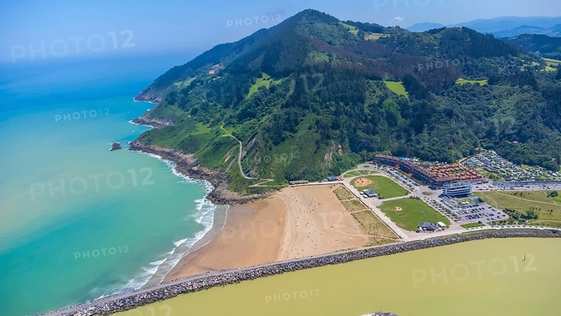Aerial perspective captures the stunning coastal beauty of orio, spain, showcasing the beach, turquoise waters, lush green mountains, and vibrant cityscape.