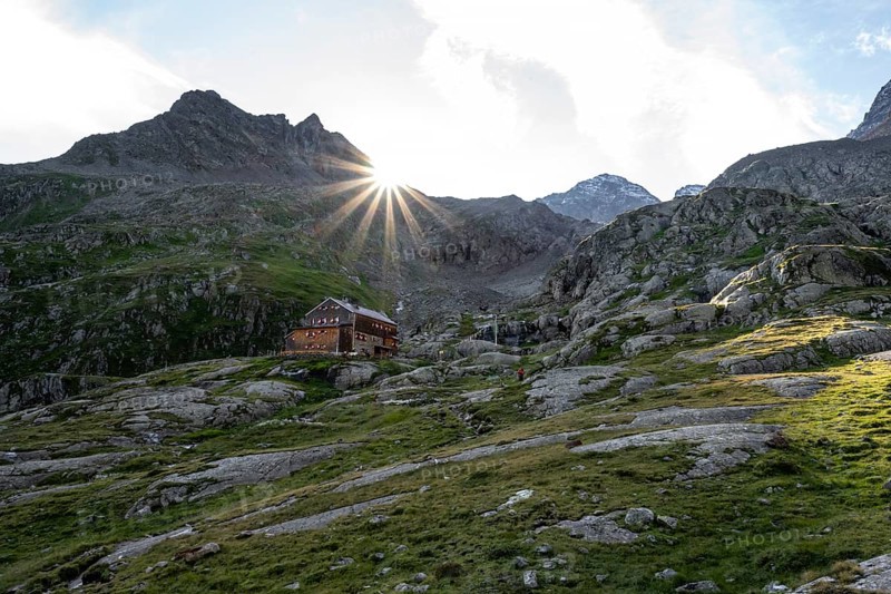 Mountain hut Elberfelderhütte in front of a rocky mountain landscape, sun star in the morning, in the upper Gössnitz valley, Wiener Höhenweg, Schober group, Hohe Tauern National Park, Carinthia, Austria