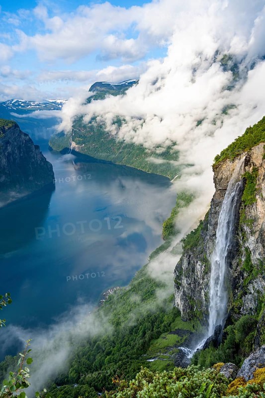 Gjerdefossen waterfall, at Ørnesvingen viewpoint, atmospheric clouds over the fjord in the morning light, at Geirangerfjord, near Geiranger, Møre og Romsdal, Norway