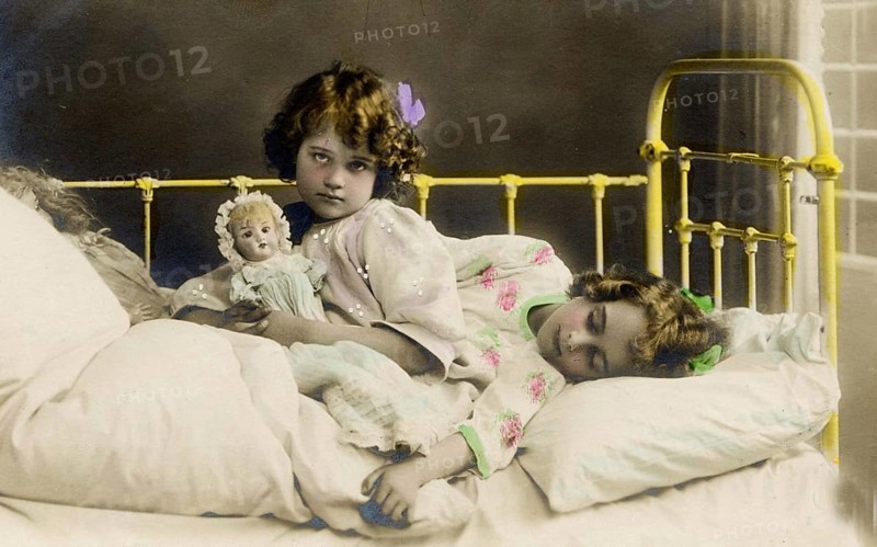 2 girls bed doll, 1920s, Two girls in a bed, one holding a doll, nostalgic and peaceful atmosphere, Historical photo