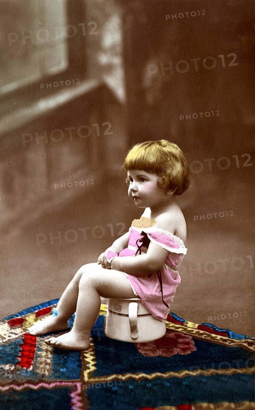 Child sitting on chamber pot, 1920s, A small child sits on a potty, smiles and wears old-fashioned clothes, Historical photo